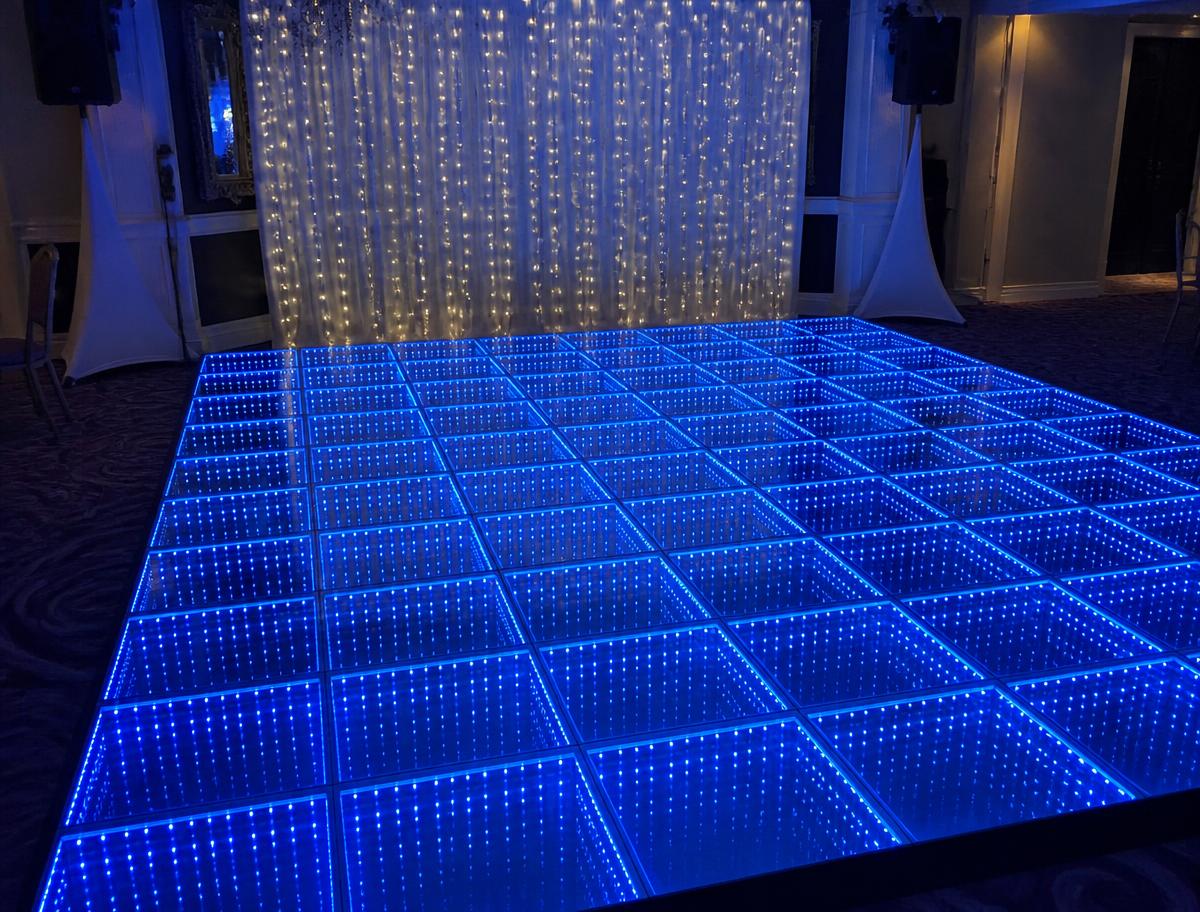 Blue infinity dance floor set up in front of fairy light curtains